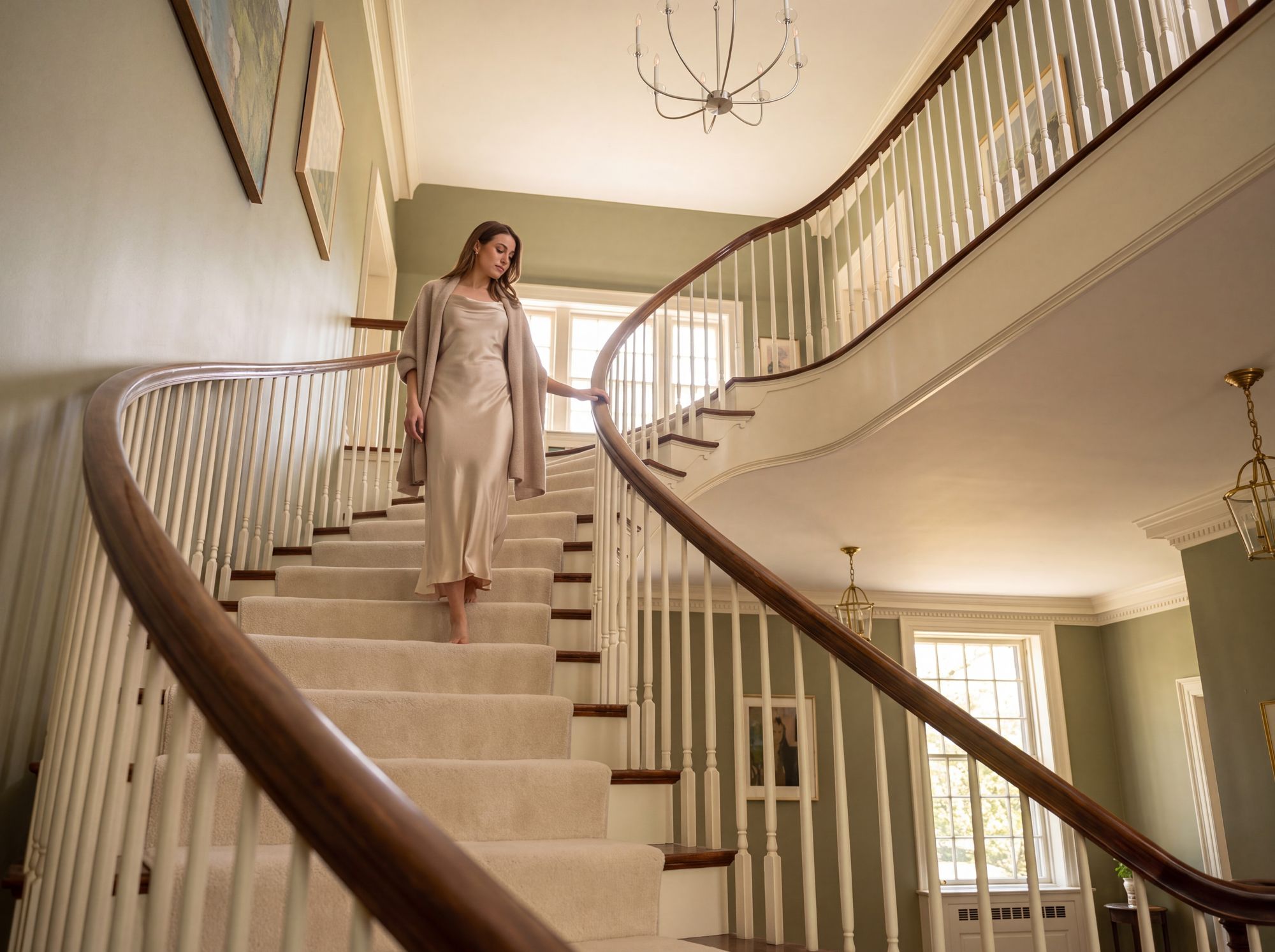 A woman descending the manor’s curved staircase