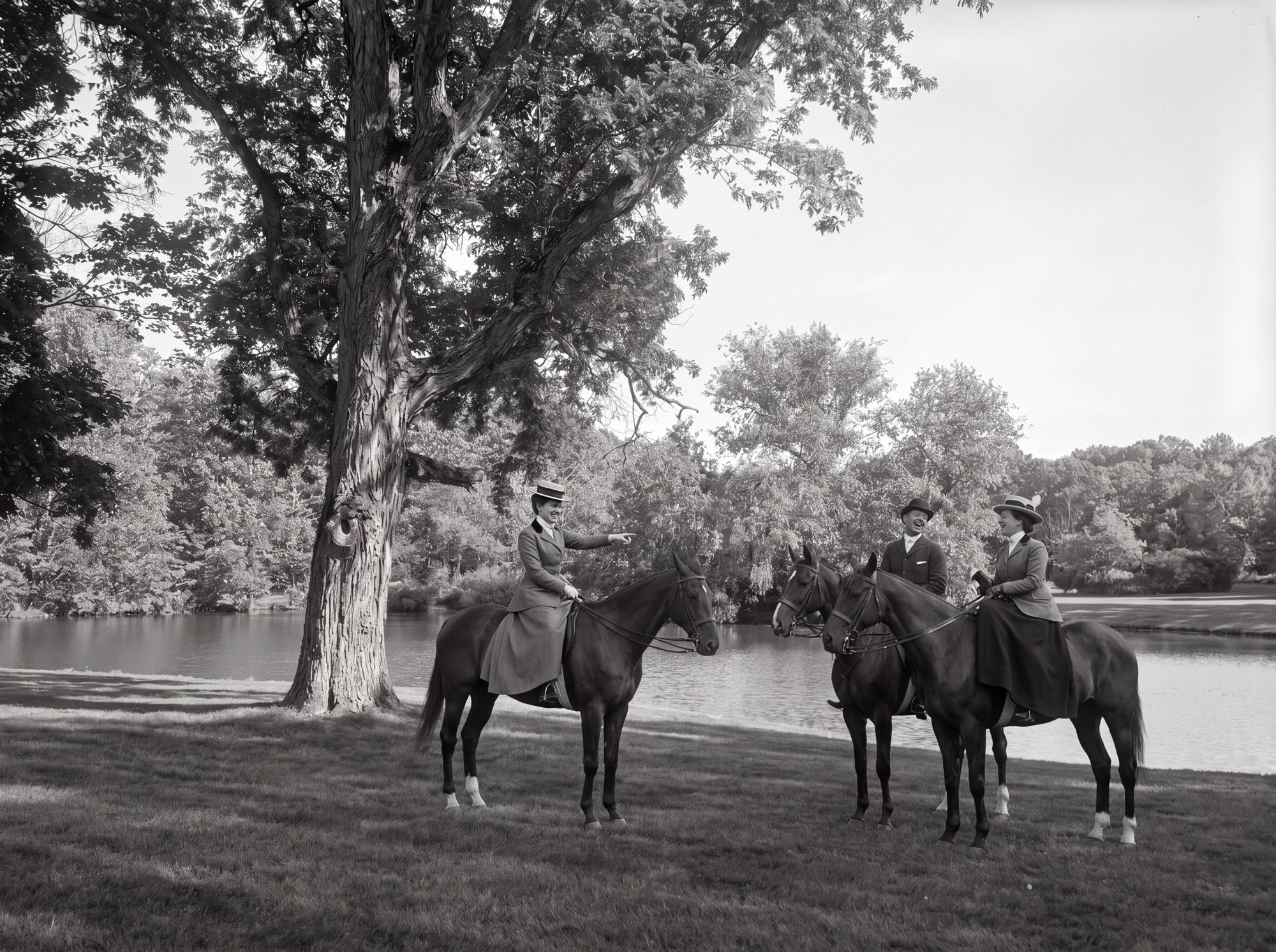 Three riders on horseback beneath a large tree beside the lake